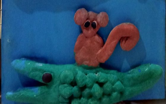 Close-up of a tactile clay painting of the monkey riding on the crocodile's back