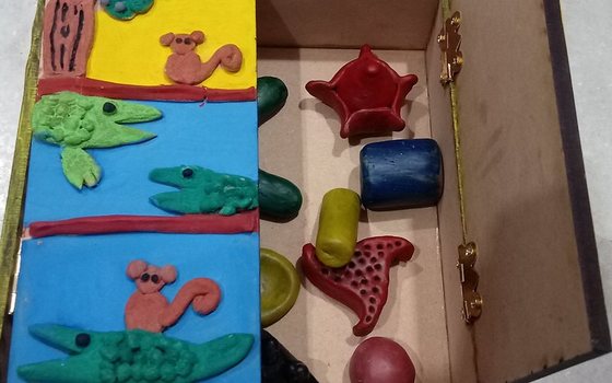 The open StoryBox seen from above, with tactile painting panels and clay figurines stored inside